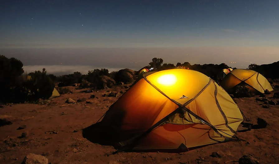 A tent at a desert campsite looking out at the sunset